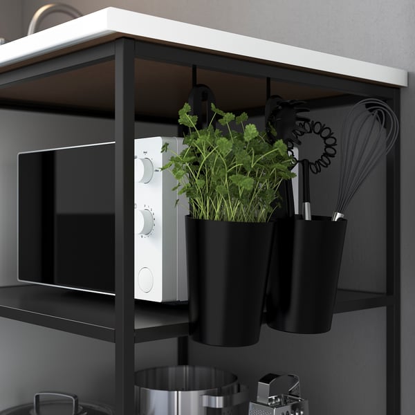 Kitchen counter with built-in microwave, hanging herb planters, and utensils.