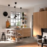 Modern kitchen with white & wood elements, marble-look counter, stainless appliances, wood cabinets, open shelving, black lights, chair.
