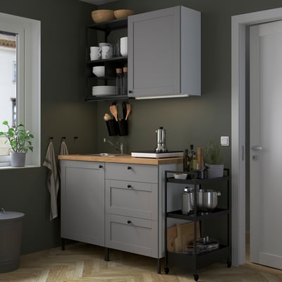 Modern gray kitchen setup with wooden counter, stainless sink, and hanging black containers.