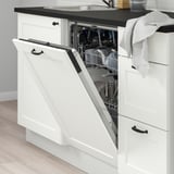 Modern kitchen scene with open dishwasher, showing clean dishes. White cabinetry with dark handles. Striped cloth draped nearby on countertop.