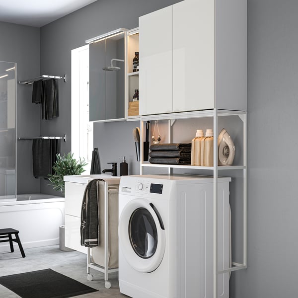 Modern gray laundry/bath combo. White washing machine, black towels, matched storage. Compact, efficient design.