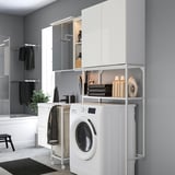 Modern gray laundry/bath combo. White washing machine, black towels, matched storage. Compact, efficient design.