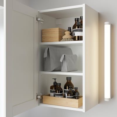 Wall cabinet with mirror door, displaying organized toiletries on shelves.