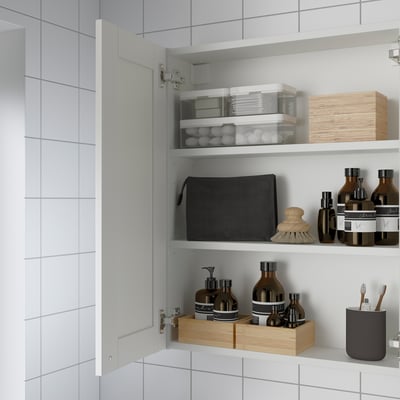 Open white cabinet with mirror door, storing bathroom items neatly on shelves.