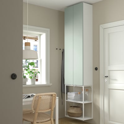 Minimalist light blue-green storage unit next to door, with open and closed sections, matches tall grey cabinet, small wicker chair.
