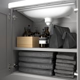 Gray bathroom cabinet with towels, toiletries, and a wooden box.