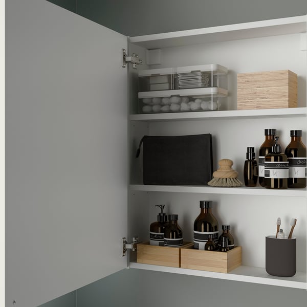 Cabinet with shelves stores bathroom items; clear, black, and wooden containers hold toiletries; mounted securely to wall.