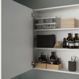 Cabinet with shelves stores bathroom items; clear, black, and wooden containers hold toiletries; mounted securely to wall.