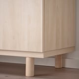 Light wooden cabinet with smooth, light-colored finish. Three cylindrical legs for support, displaying fine craftsmanship.