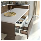 Modern kitchen drawer with push-to-open feature in silver, containing organized utensils and tools, sleek and handle-free design.