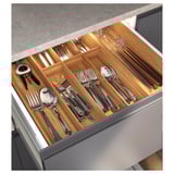 Modern handle-free kitchen drawer, gray top, white body, organized cutlery.