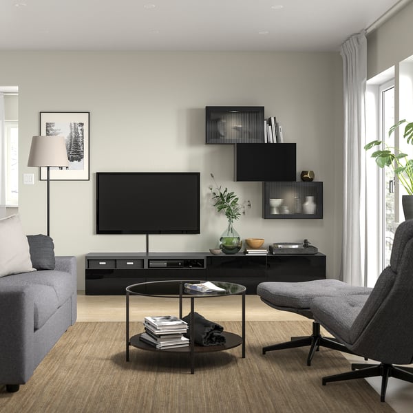 Modern living room with grey sofa, tv, coffee table, books, reeded shelves, large window, curtains, floor lamp.