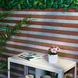 Outdoor table with magazine and pink flowers against wall.