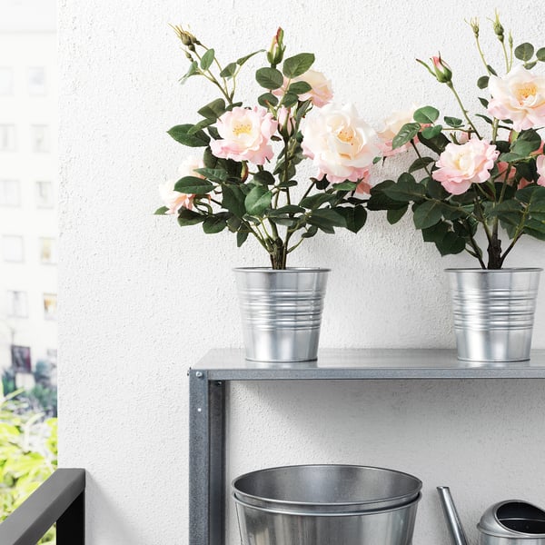 Two potted artificial flowers on a metal shelf, easy to maintain, suitable for indoor or outdoor use.
