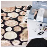 A sewing workspace with FJÄLLTÄTÖRT log-pattern fabric, scissors, and a sewing machine.