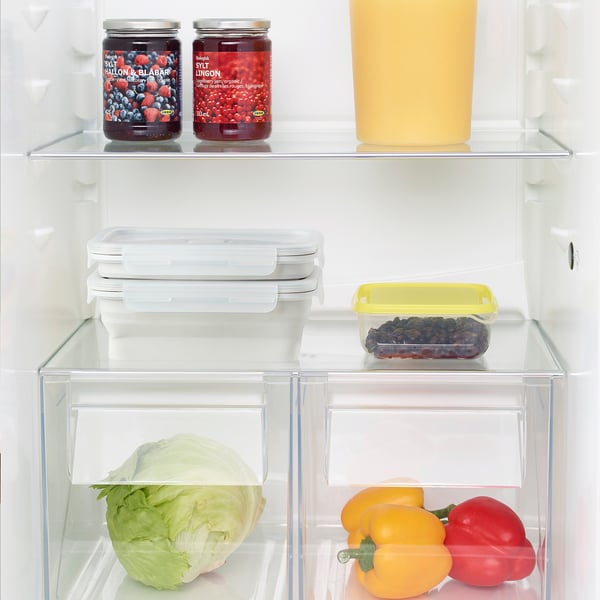 Fridge organized with veggies, jams, and leftovers.
