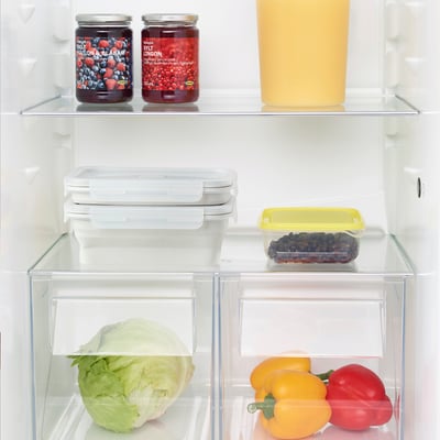 Fridge organized with veggies, jams, and leftovers.
