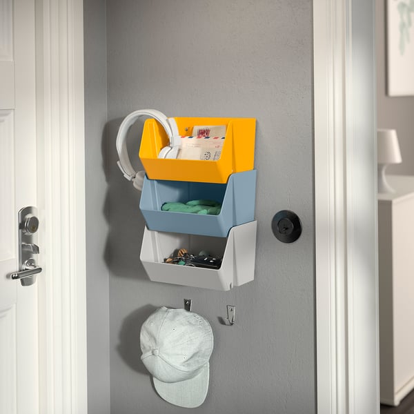 Organization system with baskets for mail, keys, and cap, mounted on wall.