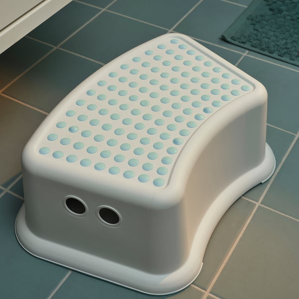White childs step stool with blue dot texture, rounded edges, and slip-resistant underside on a tiled floor.