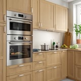 Modern kitchen with stainless steel double oven, wood cabinets, and countertop appliances.