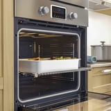 Stainless steel oven with digital display and wide glass door displays fan-forced convection cooking a colorful dish.