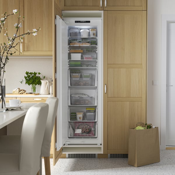 Open integrated freezer reveals organized drawers and shelves in a kitchen setting. Led lighting illuminates stored items.