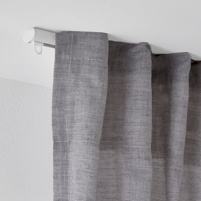 White ceiling-mounted curtain rail with gray textured curtains, showcasing FRAMFUSIGs adjustable rail system.
