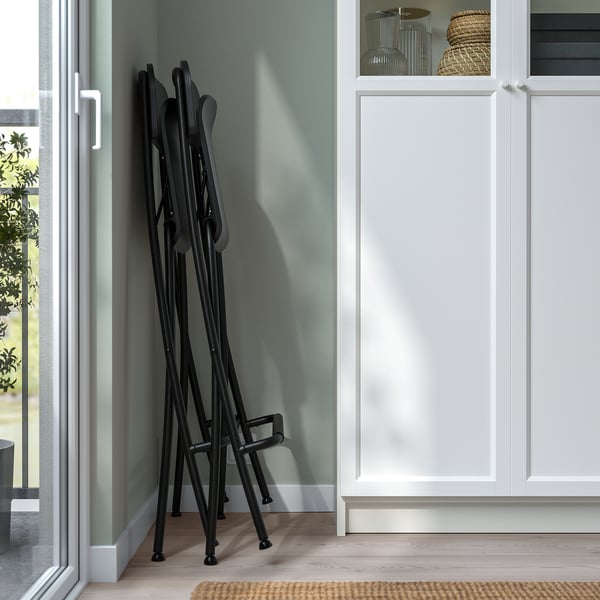Foldable bar stools stacked neatly against wall, ready for storage.