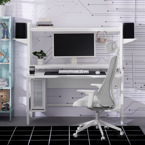 White gaming desk with monitor, keyboard, and ergonomic chair. Shelf for small items, desk supports large monitor, chair fits under desk.