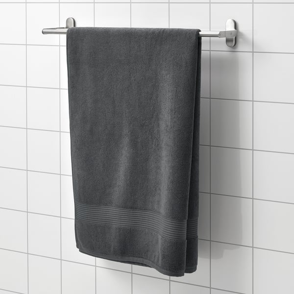 A gray FREDRIKSJÖN towel hangs on a stainless bar, partially covering a white-tiled wall.