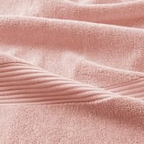 Closeup of luxurious, soft pink FREDRIKSJÖN towel showcasing its thick, plush texture and elegant woven border.
