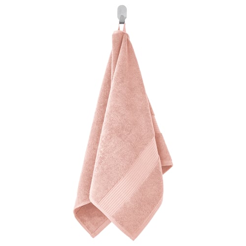 A hanging peach-colored FREDRIKSJÖN towel, soft and thick made of cotton, with a ribbed design.