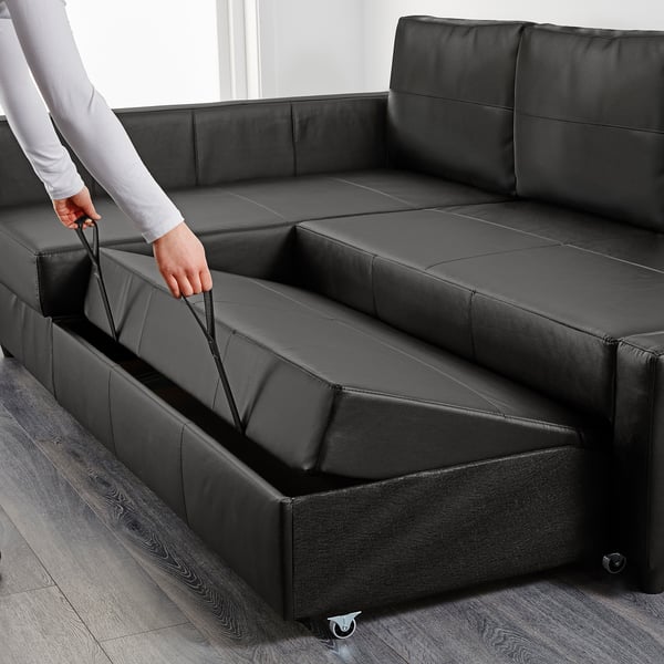 Person opens hidden storage under black sofa. Sofa has practical compartment for bed linens.