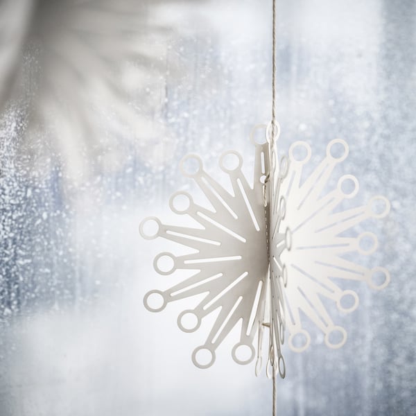 Delicate white paper decoration shaped like fireworks. Hangable festive garland with intricate cut-out designs.