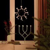 A cozy lit winter snowflake lamp hangs from the ceiling, with a modern white metal design, casting warm light.