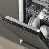 Modern dishwasher showing digital display 3:35 and open racks with clean dishes.