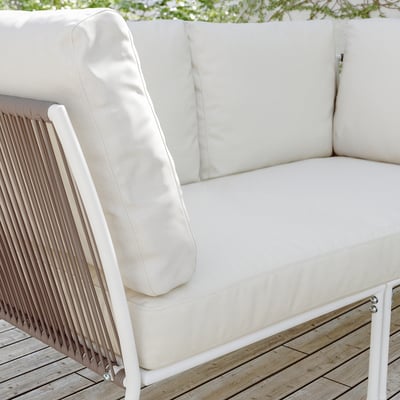 White patio loveseat with cushions on wooden deck.