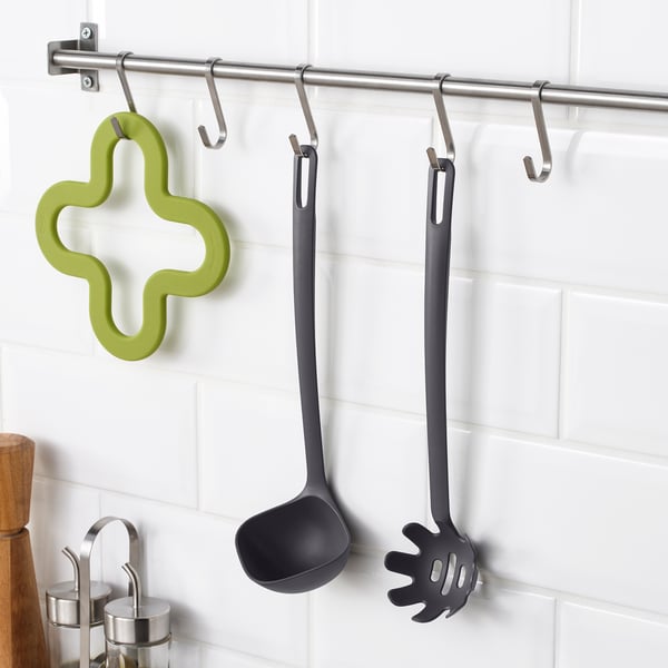 Metal rack with hanging gray utensils, including a ladle and spaghetti server, plus a green silicone mold.
