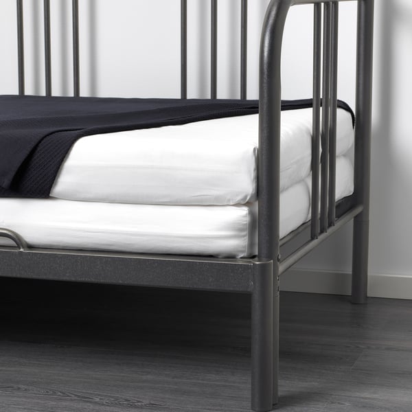 A black metal daybed with two white foam mattresses, versatile for seating or sleeping.