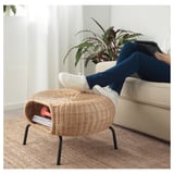 Person relaxing on couch using GAMLEHULT woven rattan footstool as a rest for feet, showcasing its use as both a footrest and extra seating.