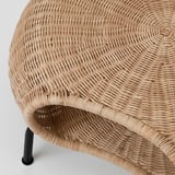 Hand-woven natural rattan footstool with intricate texture and sturdy black metal legs, showcasing quality craftsmanship and design.