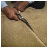 Person cuts beige GÅSHIRS wool rug with scissors. Handmade, natural, durable.