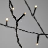 Close-up of twisted black string lights with glowing bulbs on.