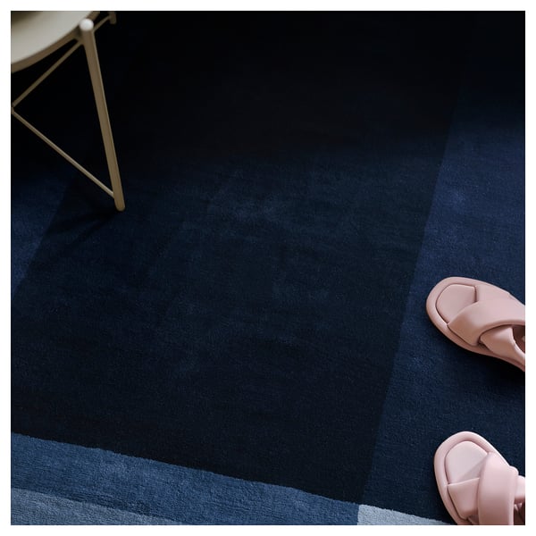 Dark blue textured rug with light blue stripes, pink slides, and white chair leg.