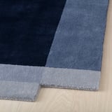Modern blue area rug, hand-woven, thick wool on wooden floor.