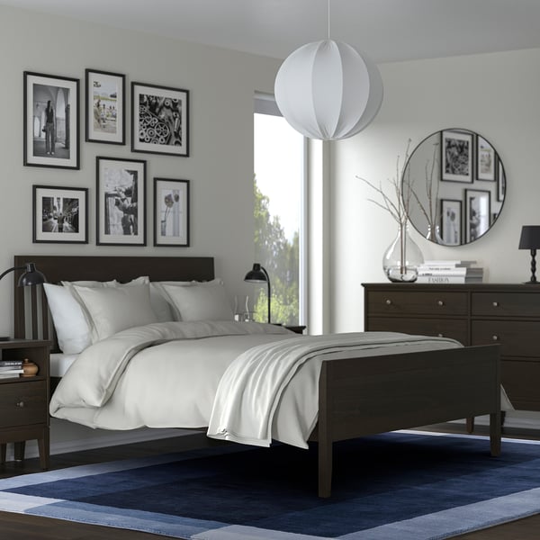 Modern blue & white bedroom: dark wood bed, white bedding, blue rug, hanging lamp, mirror, wall photos.