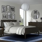 Modern blue & white bedroom: dark wood bed, white bedding, blue rug, hanging lamp, mirror, wall photos.