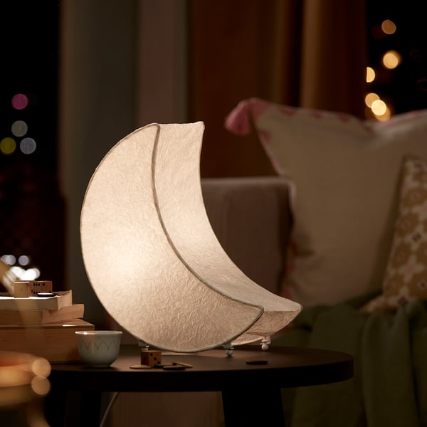 Unique crescent-shaped lamp, ideal for festive decor. GOKVÄLLÅ, white, sits on a table, smaller than books. Soft, inviting ambiance.