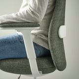 A person sitting in an ergonomic office chair with adjustable armrests and lumbar support.