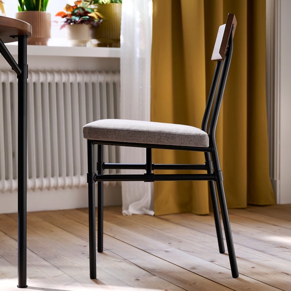 A modern chair with black metal legs and a light gray fabric seat, featuring a wooden backrest. Ideal for long seating, sturdy and stylish.